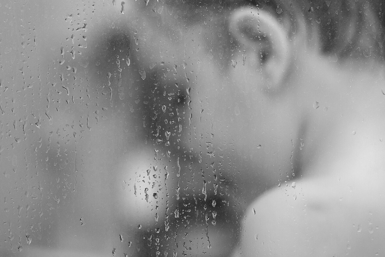 Persona tomando una ducha, vista a través del cristal